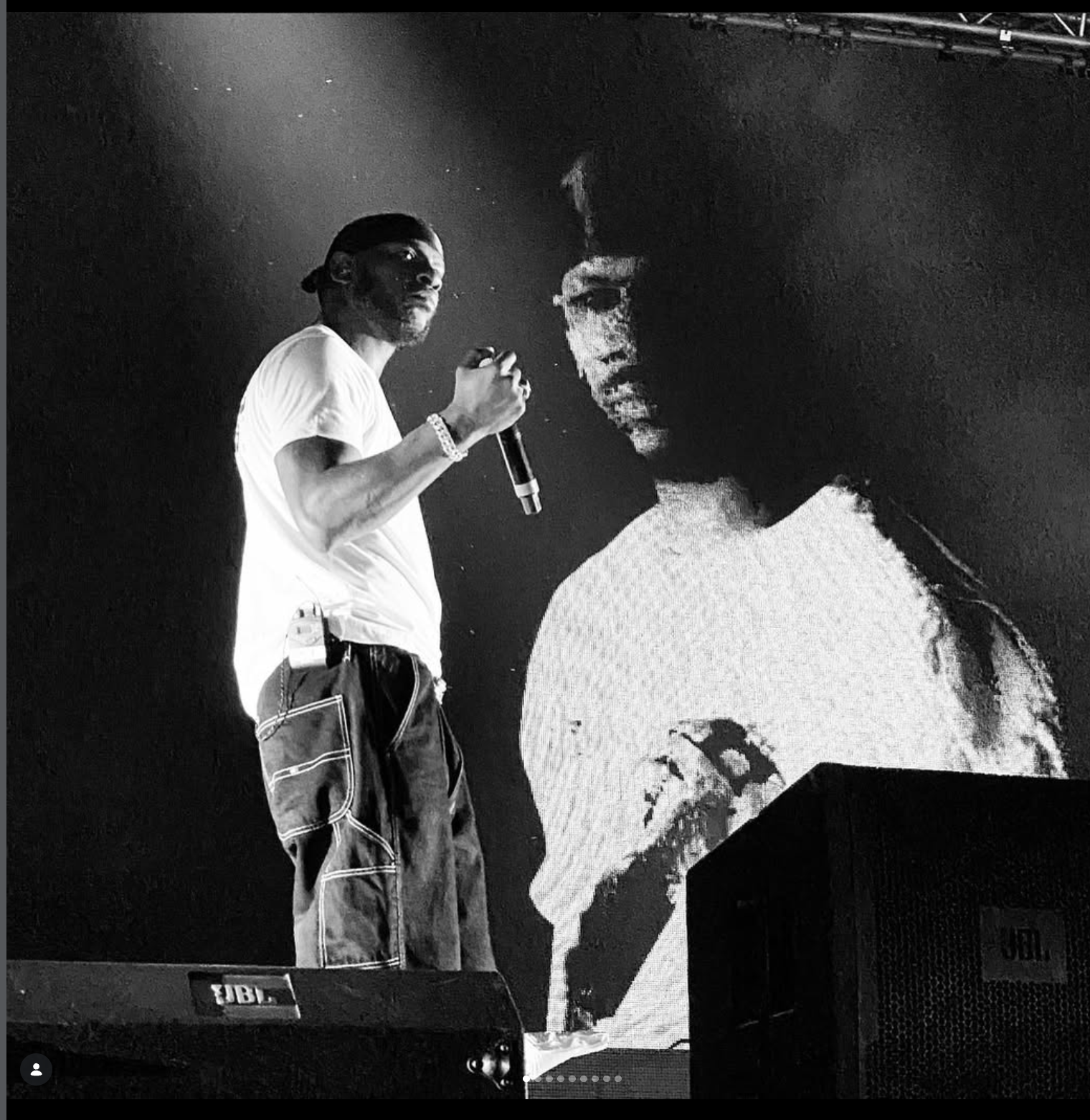 Performer holding a microphone in front of a monumental projected portrait