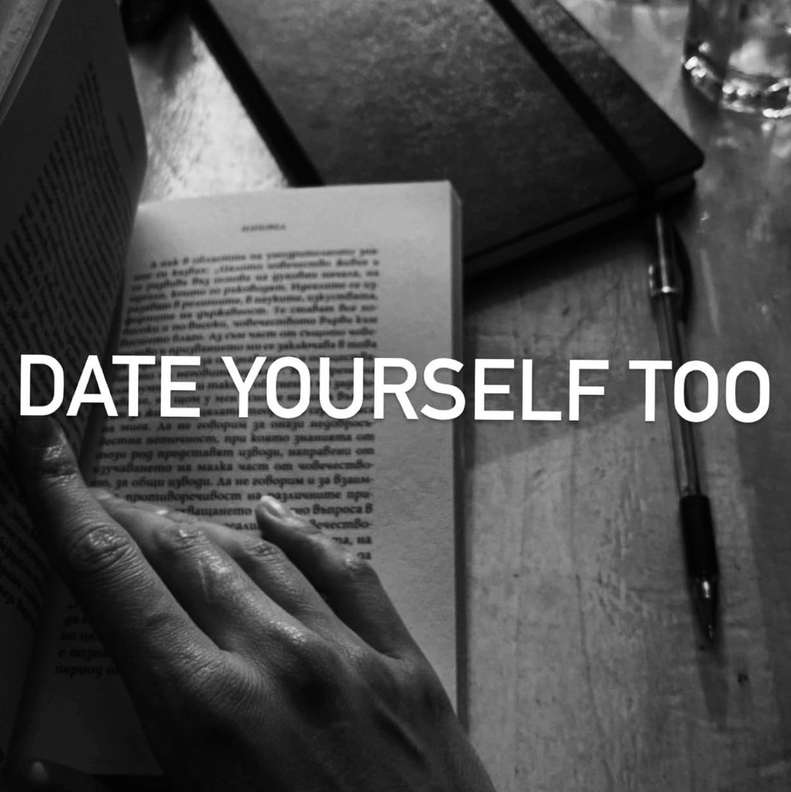 Black-and-white still life with a book, notebook, pen, and the words Date Yourself Too