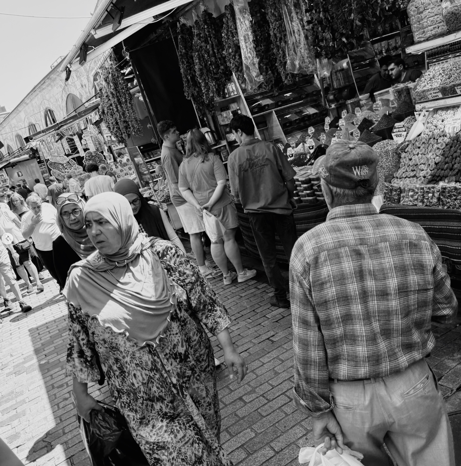 Black-and-white street scene moving through a crowded market lined with food stalls
