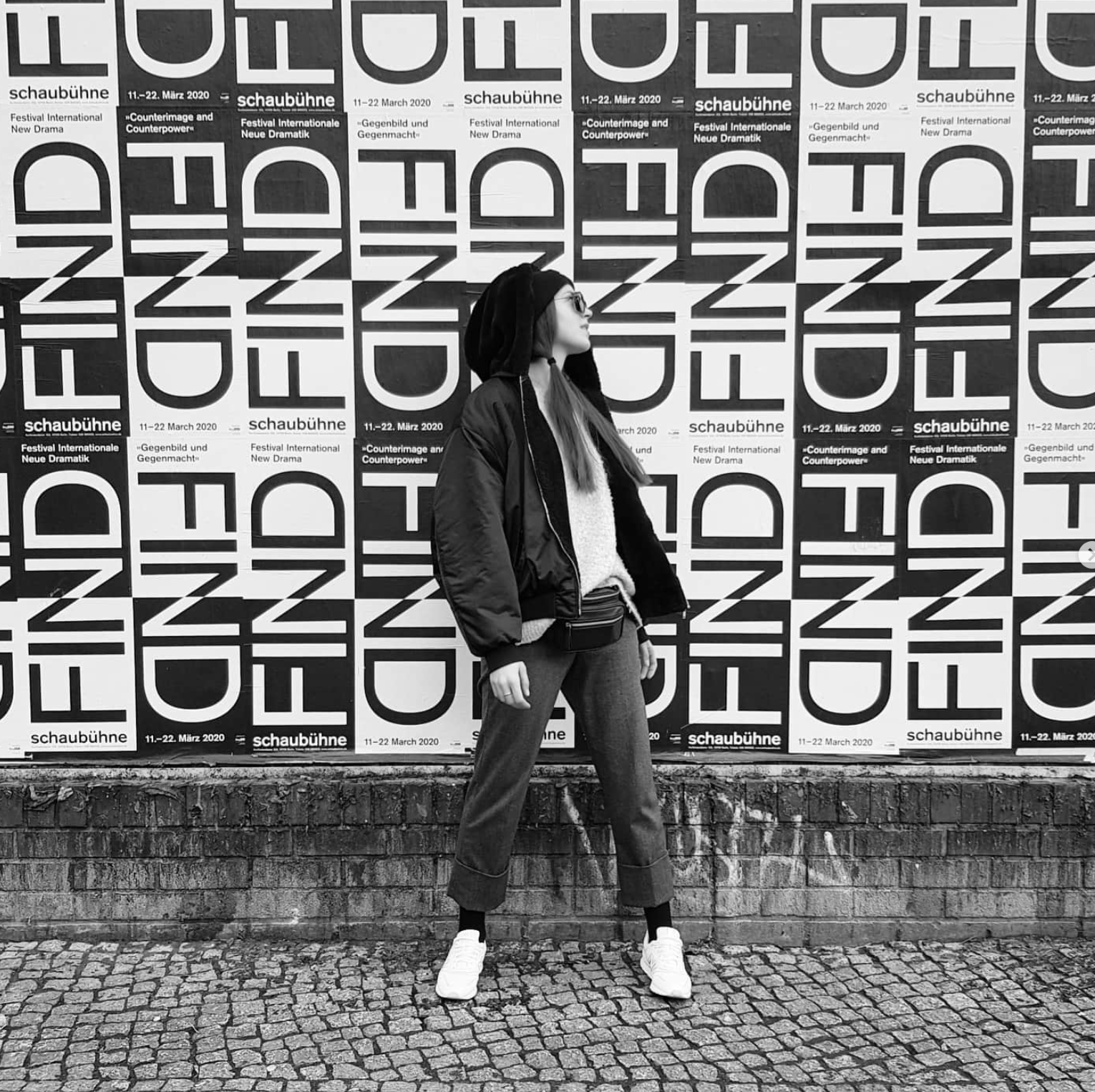 Woman standing against a wall covered in bold typographic posters
